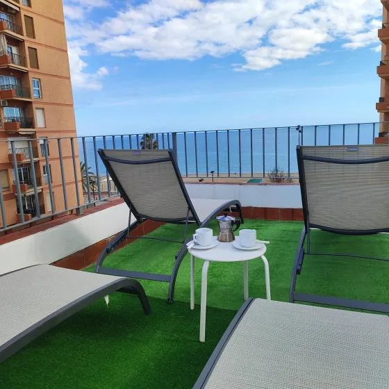 A rooftop terrace with lounge seating and a small table overlooks the sea.