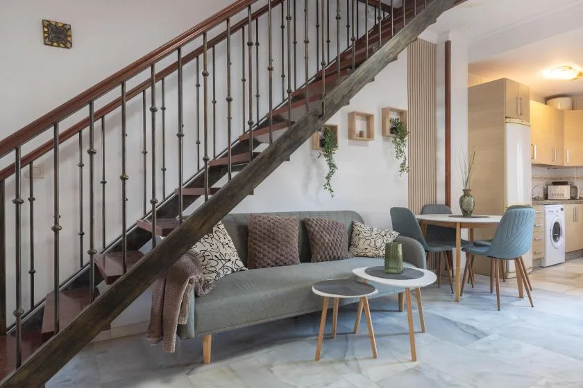 A living area beneath a staircase, with seating and a small dining table.