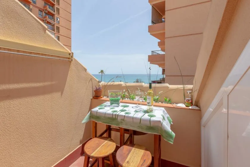 A small balcony dining area with a table overlooking the sea.