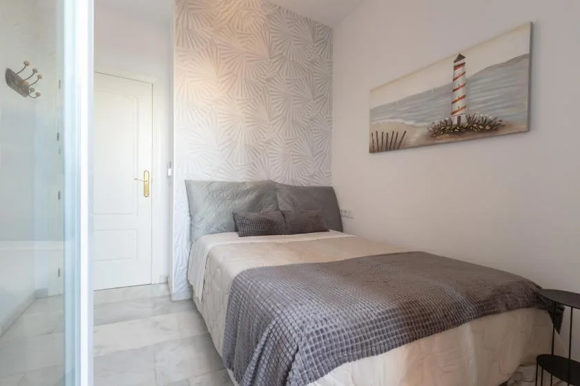 A bedroom with a bed dressed in white and gray bedding.