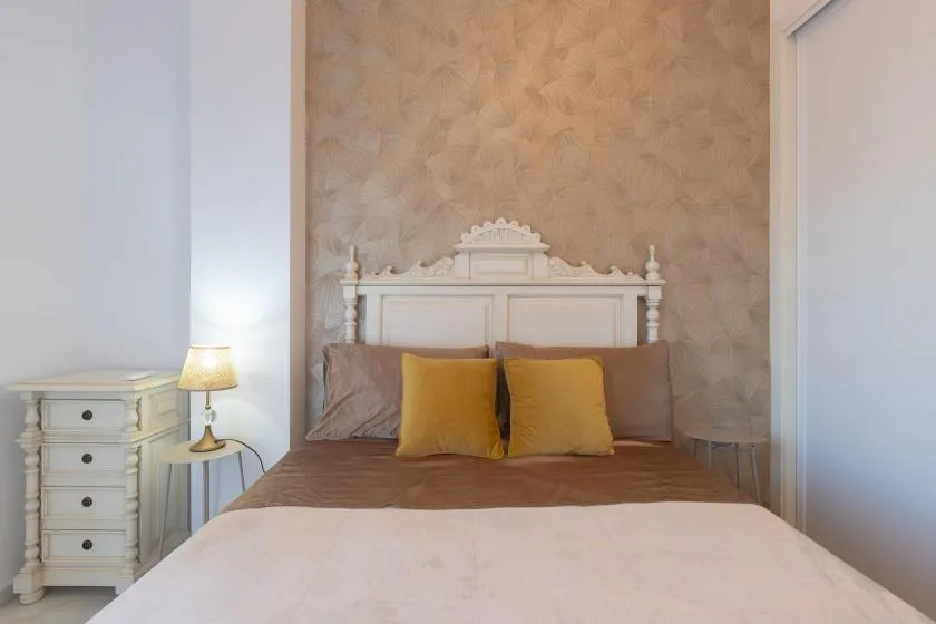 A bedroom with a bed, two yellow pillows, and a small bedside lamp.