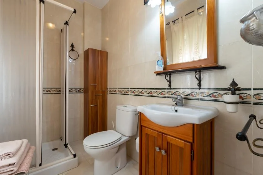 A bathroom with a sink, toilet, and glass shower enclosure.