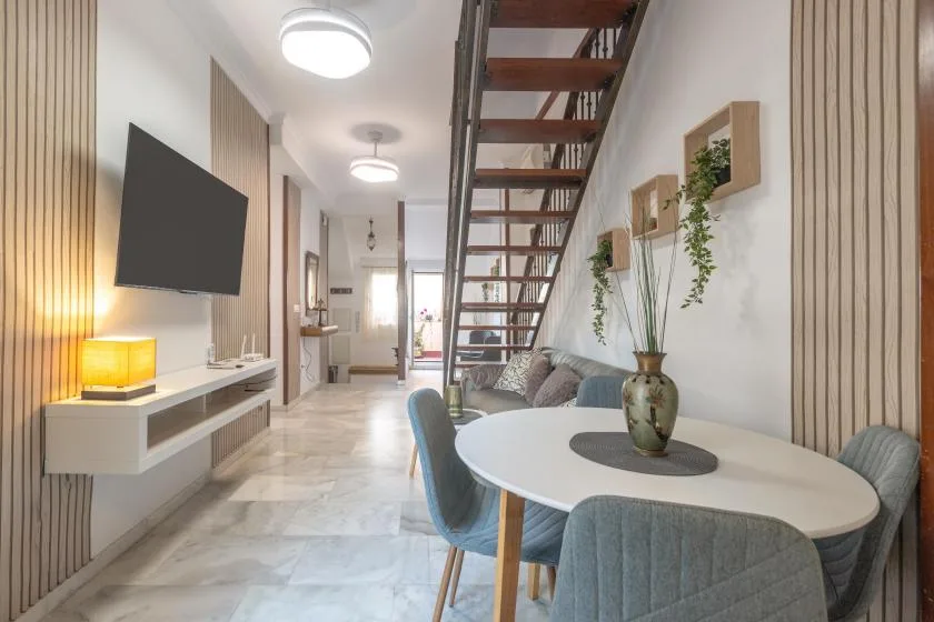 A dining area with an oval table and an open staircase beside the living space.