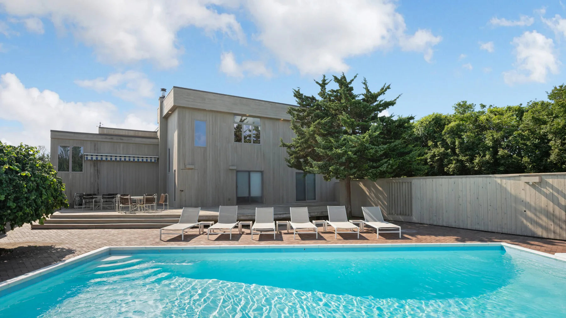 Outdoor swimming pool beside a modern building and patio seating.