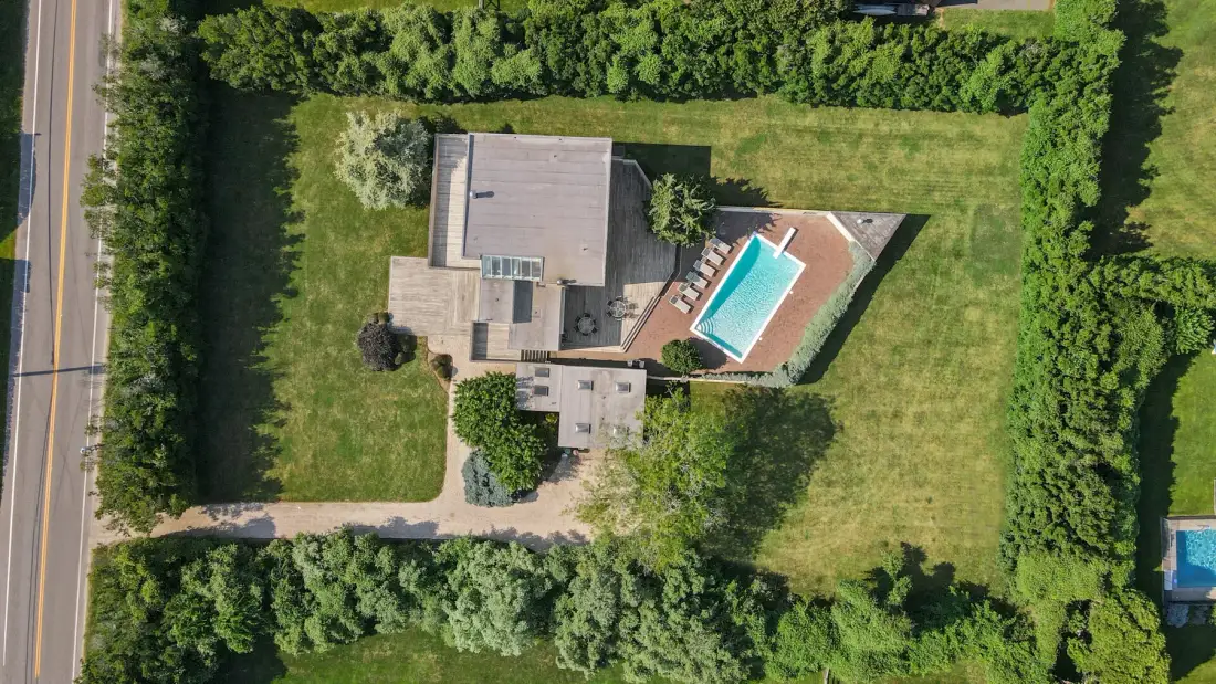 An aerial view shows a house, a swimming pool, and surrounding lawn.