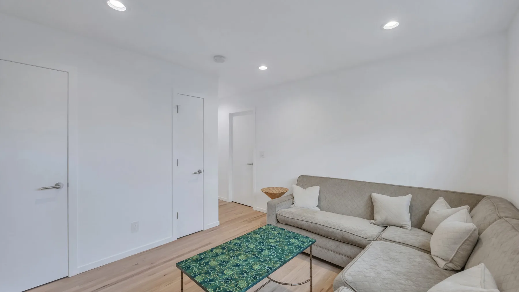 A bright living room with a sectional sofa and a patterned coffee table.