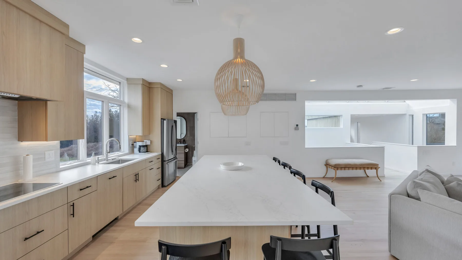 A bright open-plan kitchen and living area with a large island and pale cabinetry.