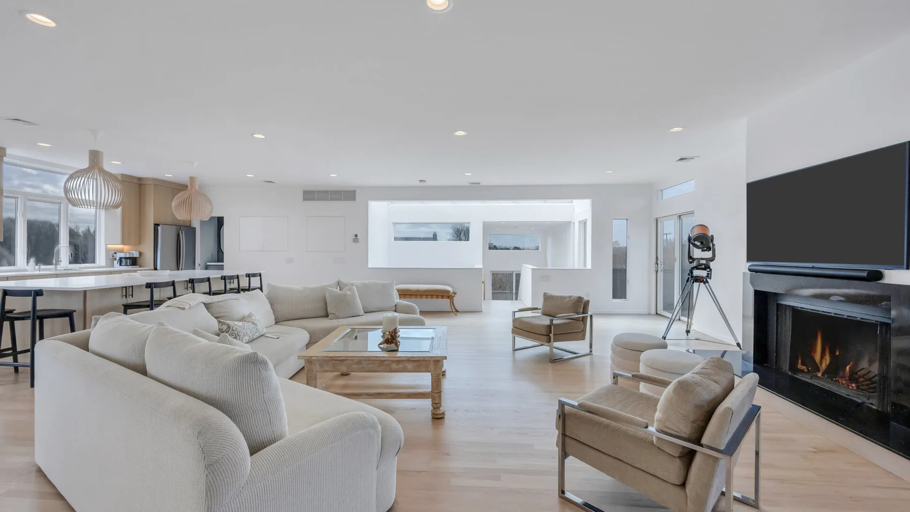 A bright open-plan living room with seating, a coffee table, and a fireplace.