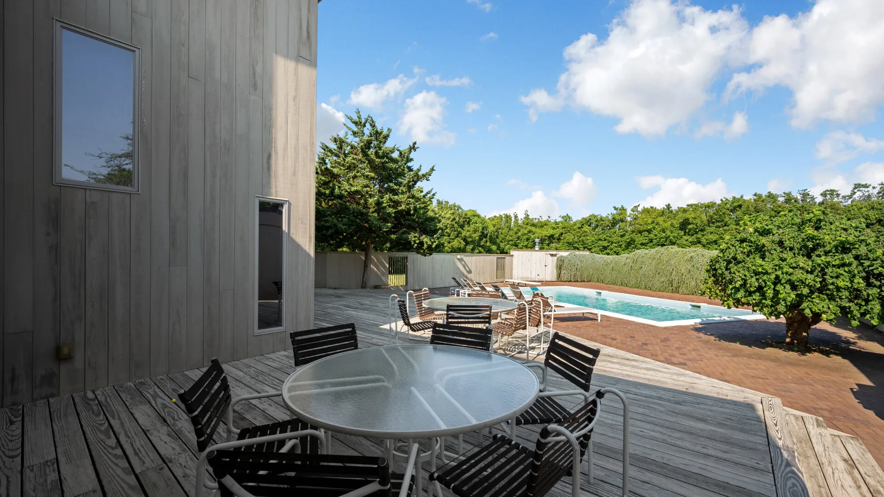 An outdoor patio with a round table and seating overlooks a swimming pool.