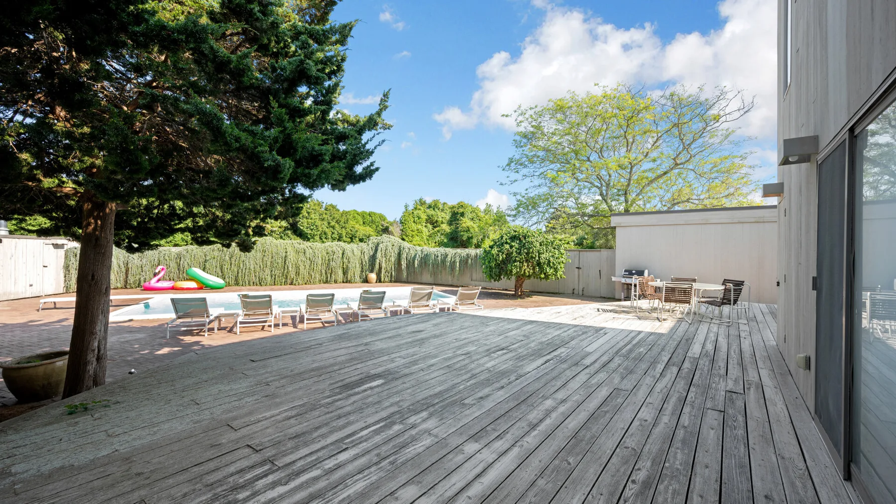 A wooden deck overlooks an outdoor pool with lounge seating.