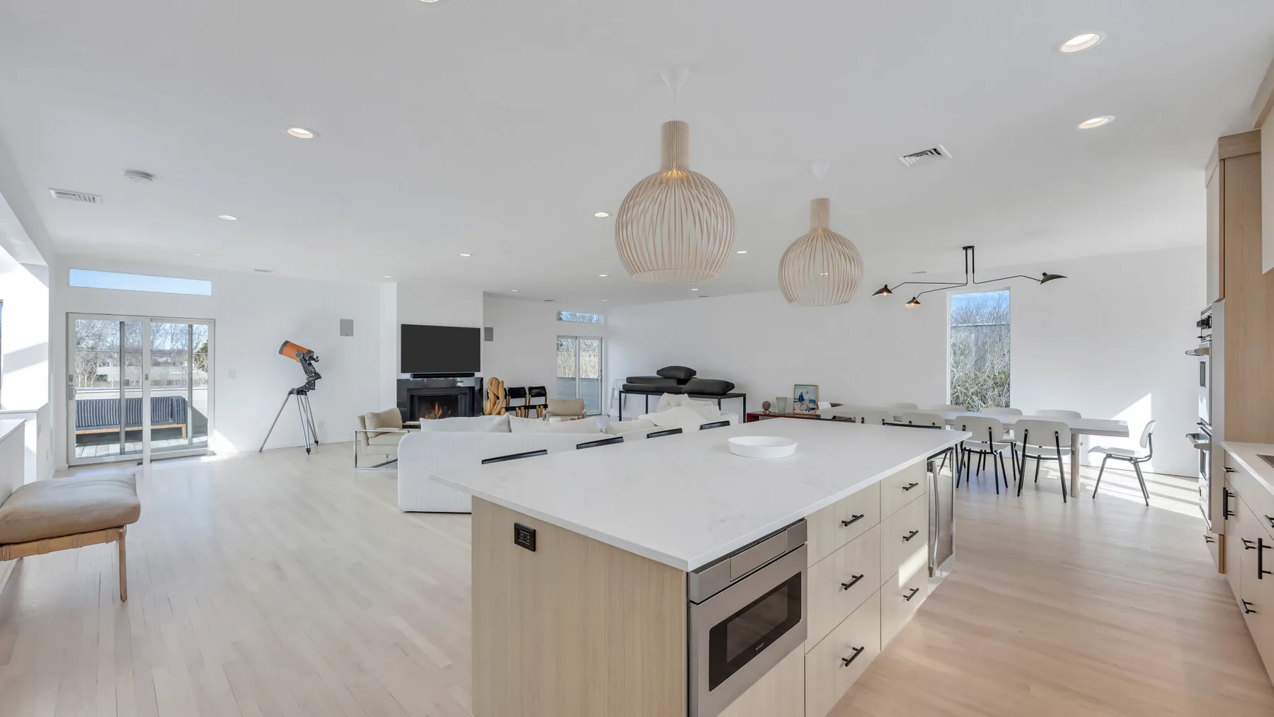 A bright open-plan kitchen and dining area with a large island and pendant lights.
