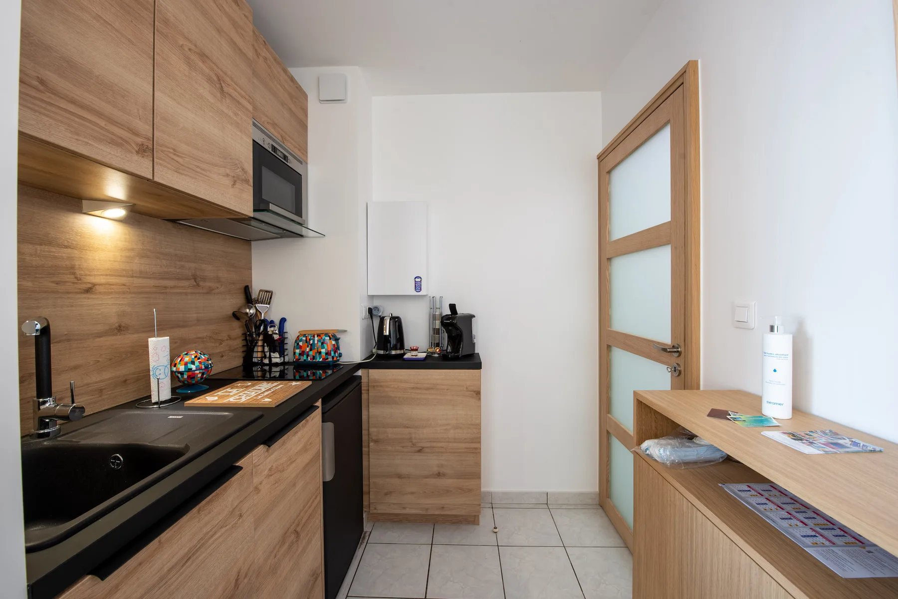 A compact kitchen with wood cabinetry, a cooktop, and countertop appliances.