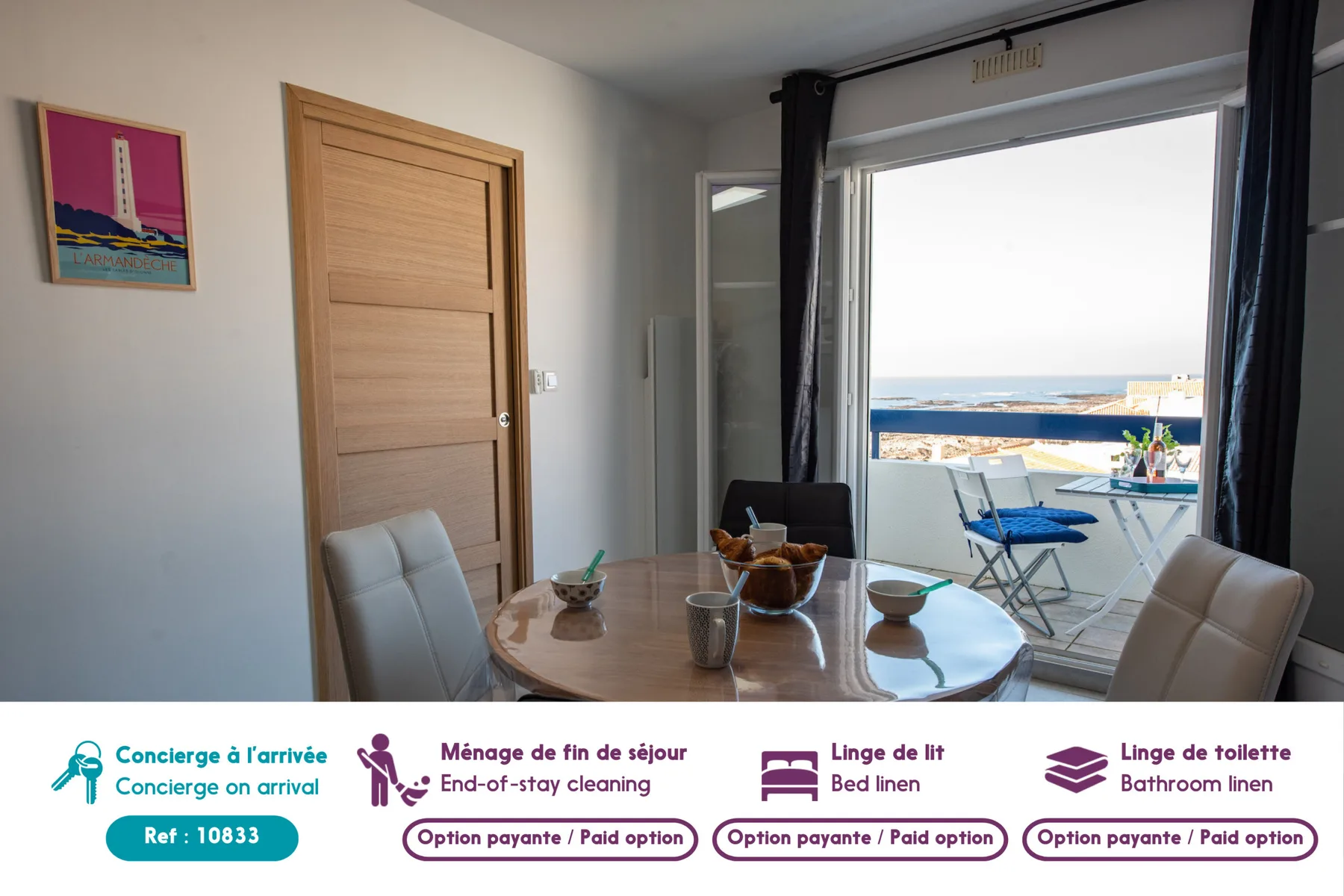 Dining area with a round table beside an open balcony overlooking the sea.