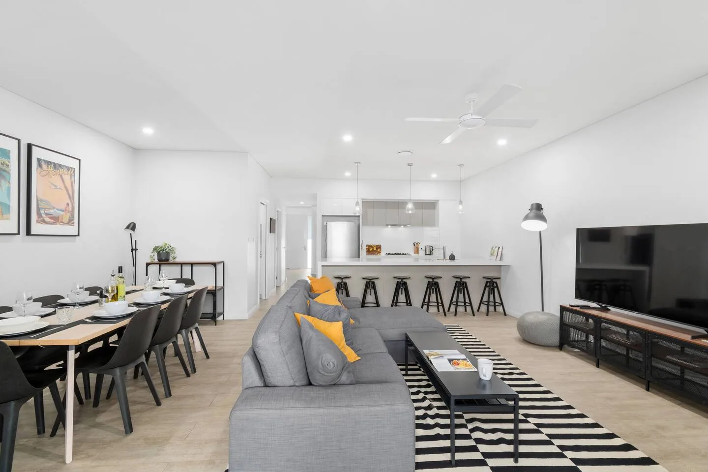 Una sala-comedor de concepto abierto con barra de cocina y asientos grises.