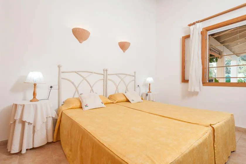 Un dormitorio con dos camas cubiertas con ropa de cama amarilla y una ventana.