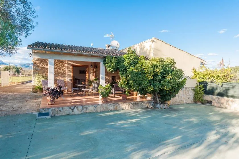 Una casa de piedra con un patio cubierto y una zona exterior pavimentada.