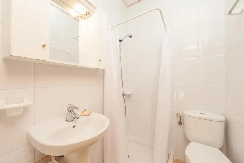 Un baño alicatado con lavabo y ducha detrás de una cortina.