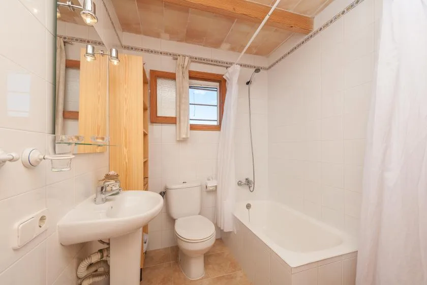 Un baño luminoso con bañera, lavabo e inodoro.