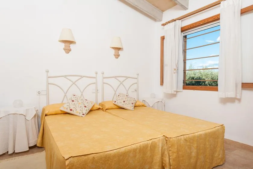 Un dormitorio con una cama doble y una ventana con cortinas blancas.