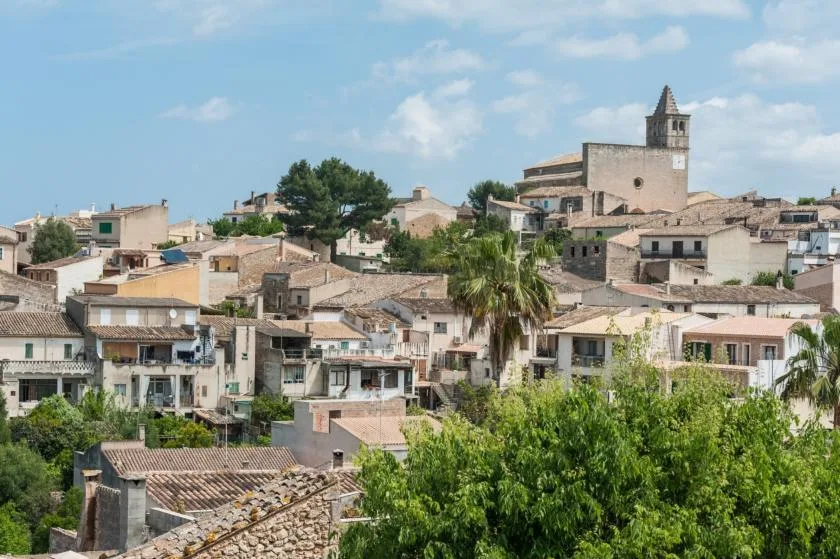 Un paisaje urbano de edificios agrupados con una torre de iglesia sobre los tejados.