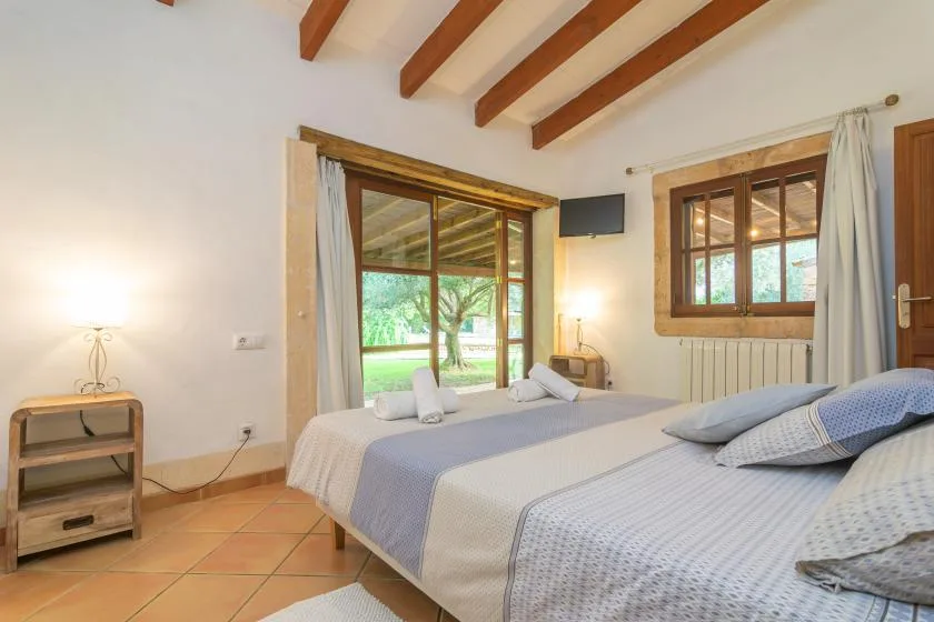 Un dormitorio con dos camas y una puerta acristalada que da a un jardín.