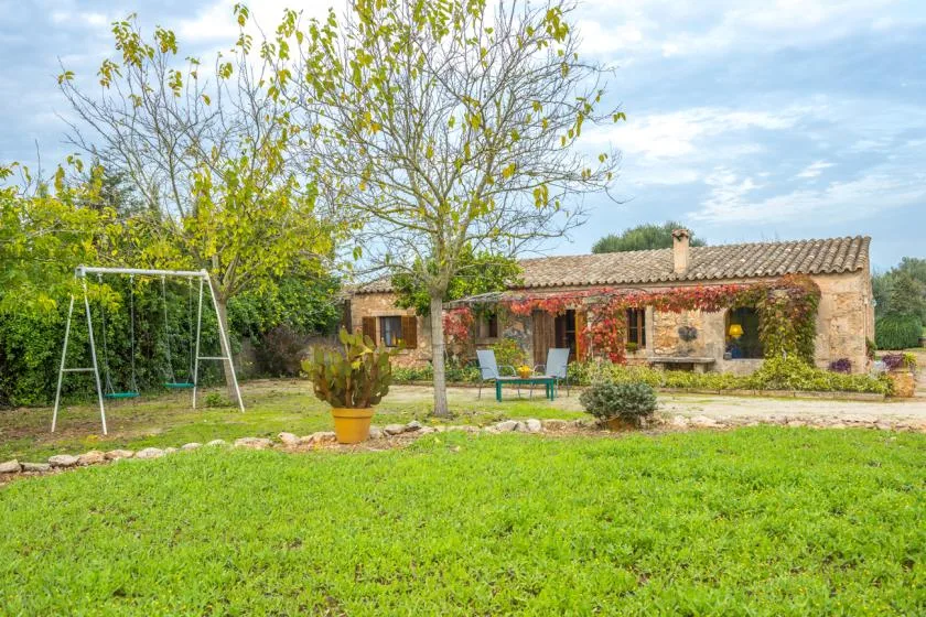 Una casa de piedra con techo de tejas junto a un césped verde y un jardín.