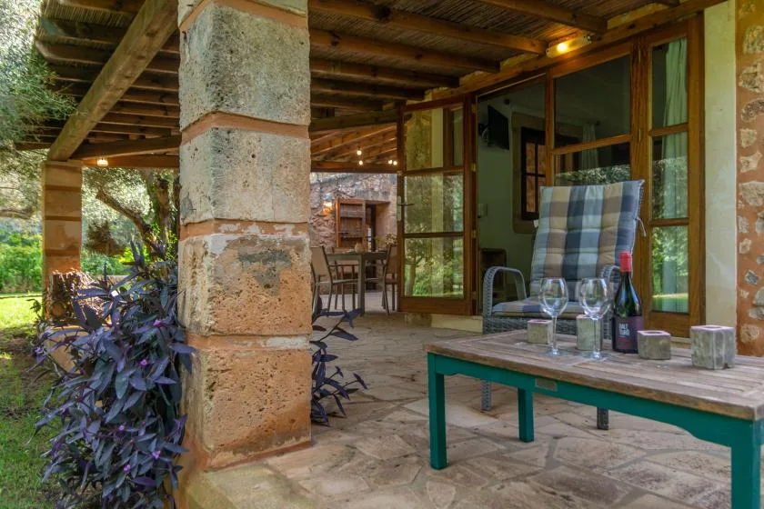Un patio cubierto con una mesa, sillas y vistas al jardín.