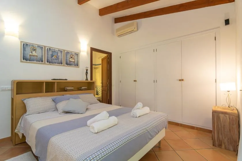 Un dormitorio con una cama doble, toallas dobladas y armarios empotrados.