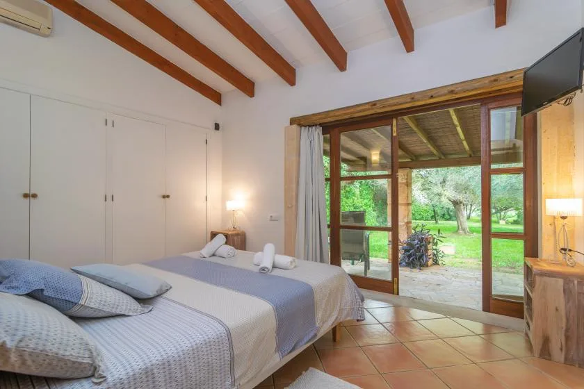 Un dormitorio con dos camas junto a grandes puertas de vidrio que dan a un jardín.