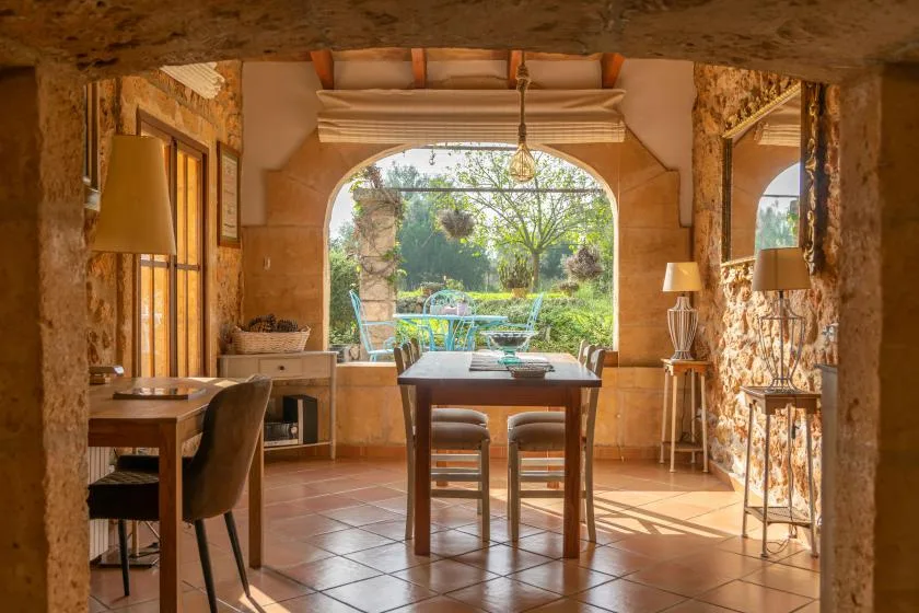 Un comedor de tonos cálidos se abre al jardín a través de una ventana arqueada.