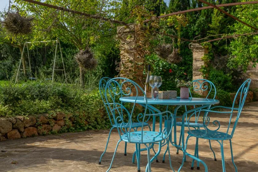 Un comedor en un patio al aire libre con una mesa turquesa y asientos metálicos.