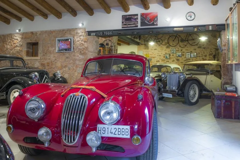 Un salón de coches clásicos muestra varios vehículos, con uno rojo en primer plano.