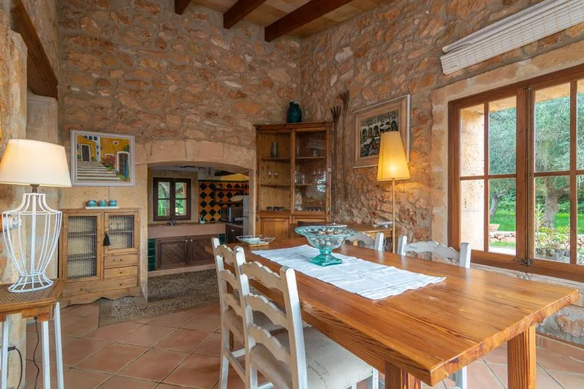 Un comedor rústico con una mesa larga de madera y ventanas grandes.
