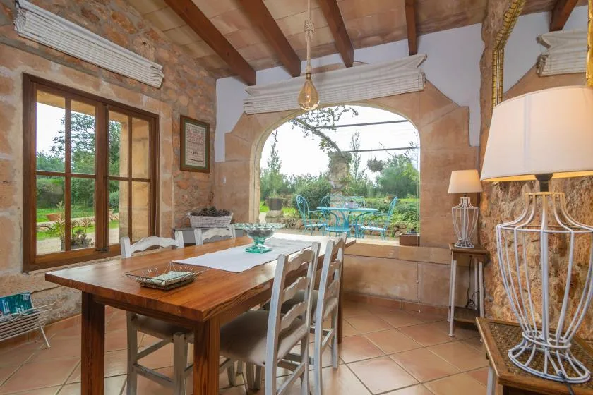 Comedor con una mesa de madera y vistas al jardín a través de una abertura arqueada.