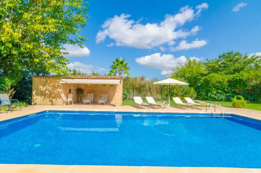 Piscina al aire libre con asientos y un patio sombreado.