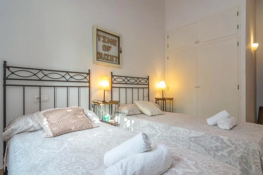 Un dormitorio con dos camas, mesitas de noche y toallas dobladas.