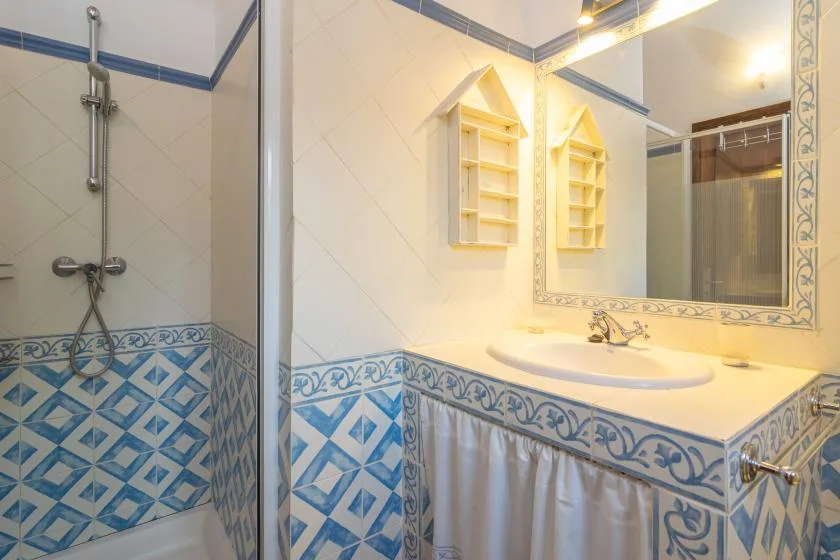 Un baño alicatado con ducha, lavabo y un gran espejo de pared.