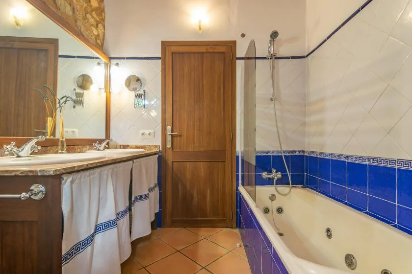 Un baño alicatado con lavabo, puerta de madera y bañera.