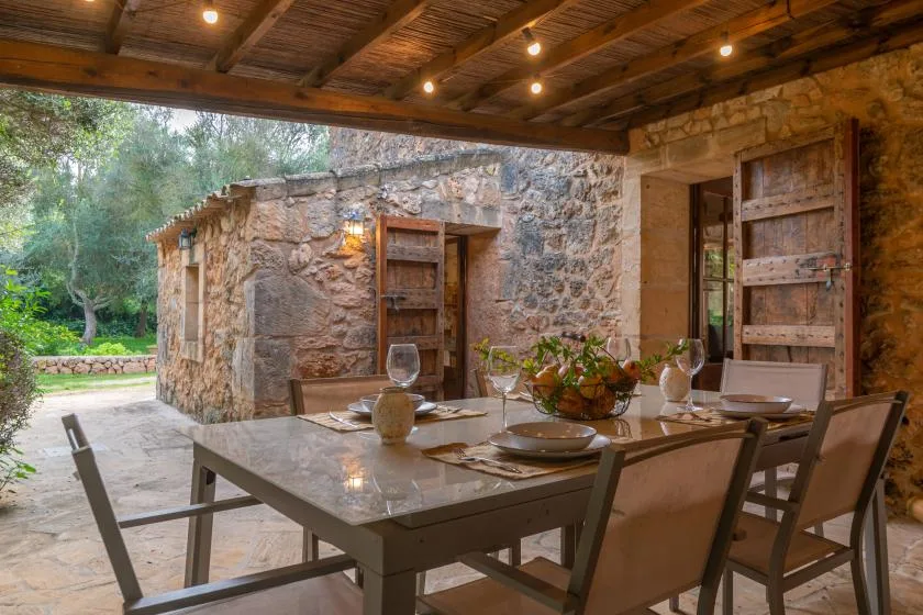 Comedor exterior cubierto con una mesa y sillas junto a paredes de piedra.
