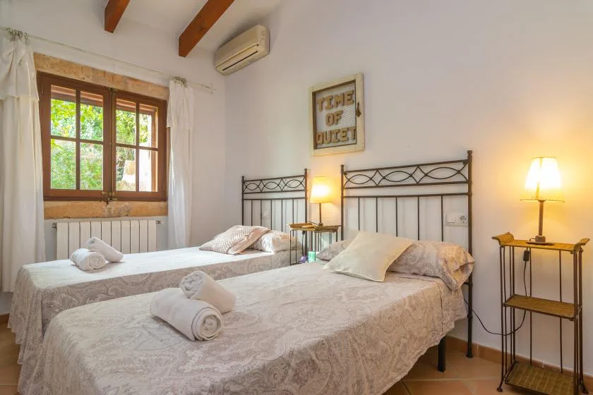 Un dormitorio con dos camas, una ventana y lámparas de noche.
