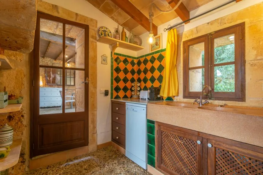 Una cocina rústica con fregadero, encimera y un salpicadero de rombos coloridos.