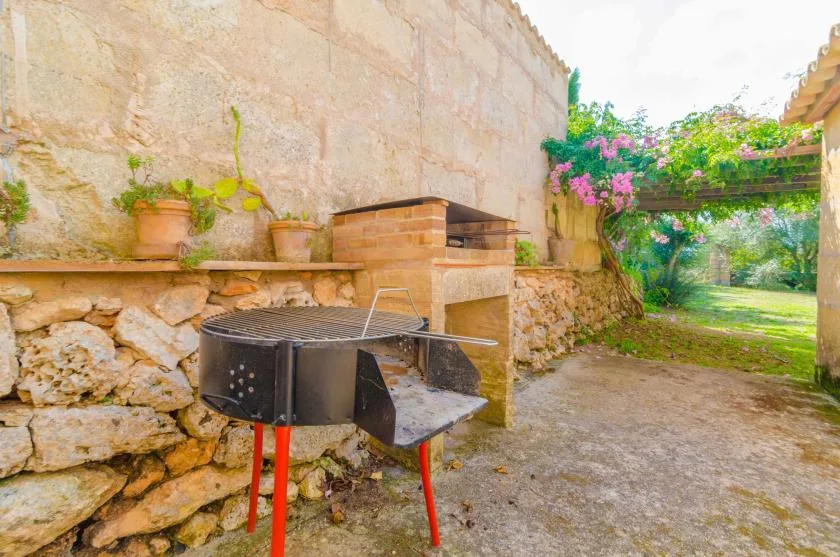 Una zona de cocina al aire libre con una parrilla junto a un muro de piedra.