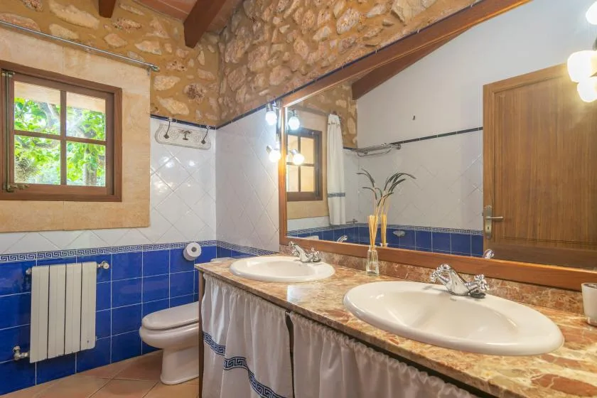 Un baño con un mueble largo, dos lavabos y azulejos azules.