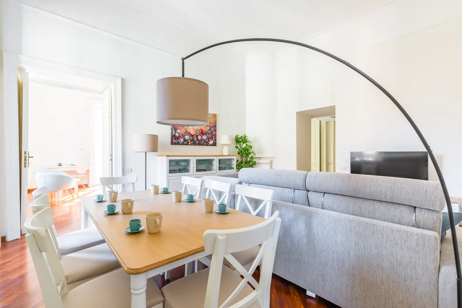 Un comedor y sala de estar luminosos, con una mesa de madera y asientos grises.