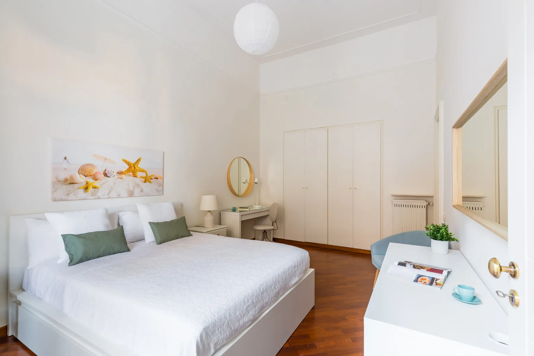Un dormitorio luminoso con una cama bien tendida y una cómoda blanca.