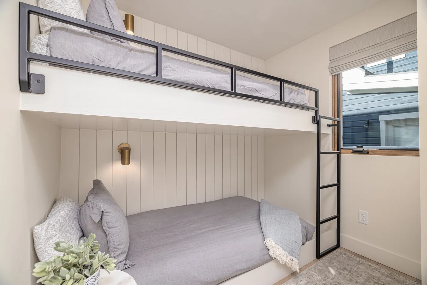 Un dormitorio con una cama gris debajo de una plataforma elevada para dormir.
