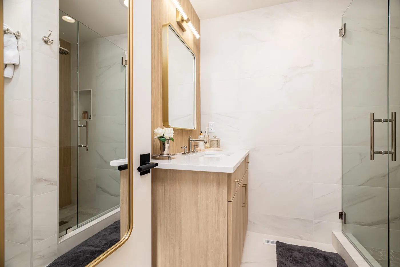 Un baño luminoso con mueble de madera, espejo y ducha de vidrio.