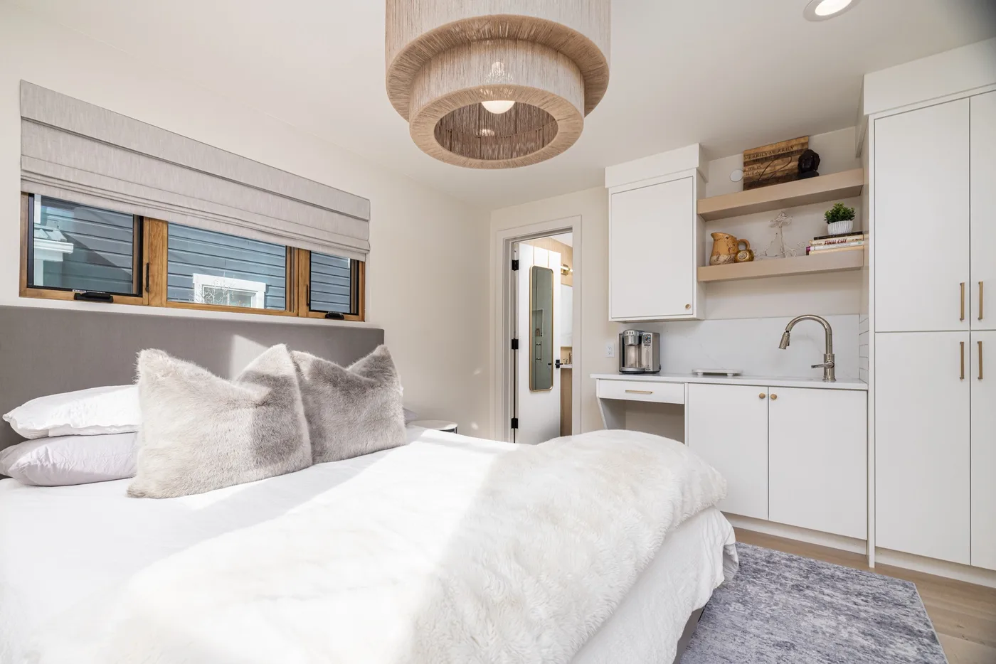 Un dormitorio luminoso con una cama junto a una pequeña cocina.