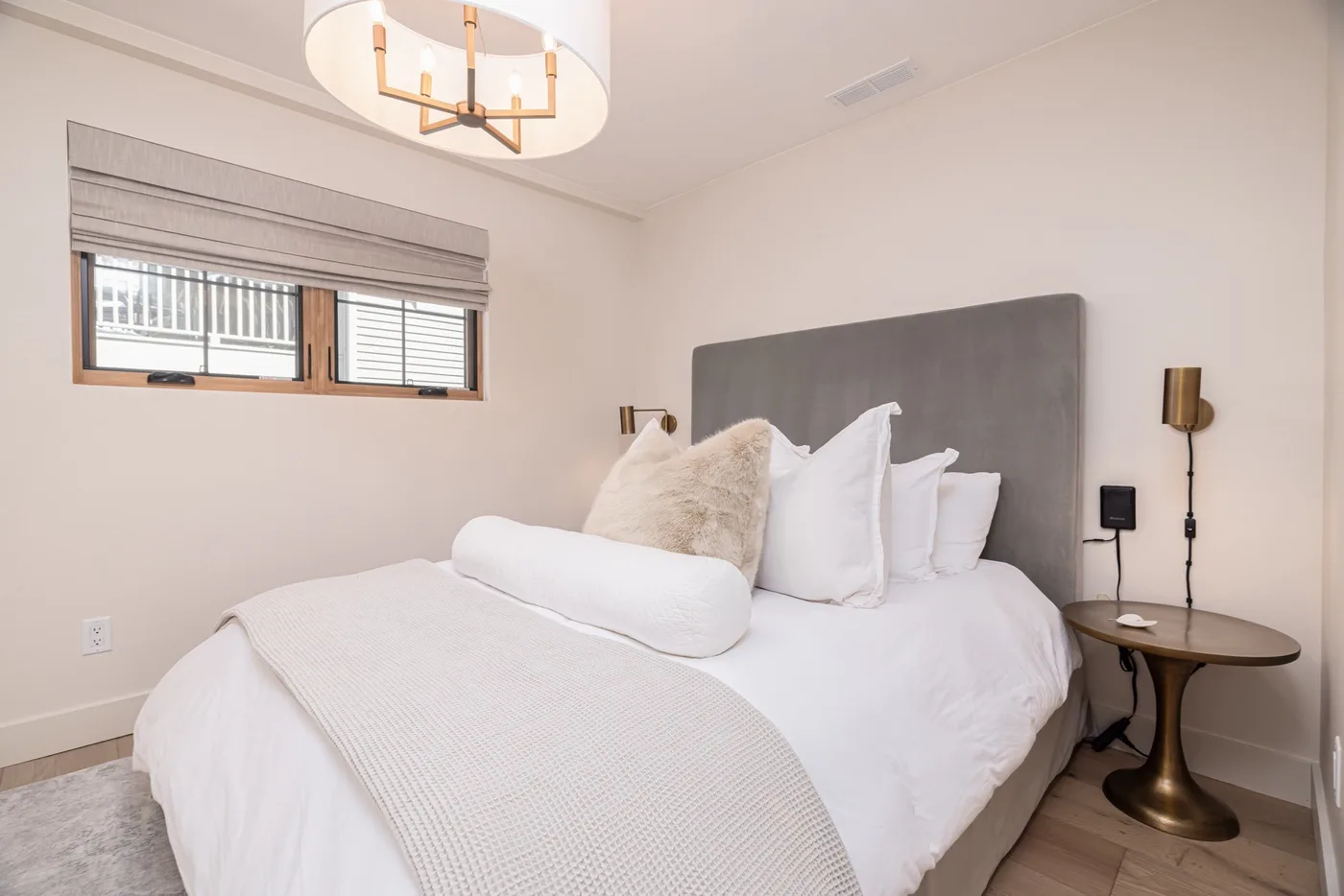 Un dormitorio con una cama bien tendida y una ventana con persianas.