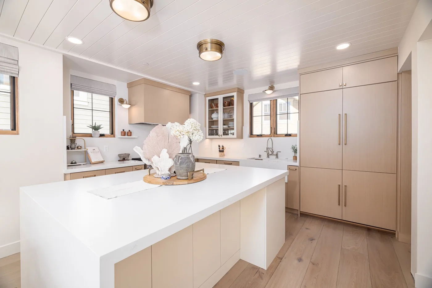 Una cocina luminosa con una isla grande y piso de madera clara.
